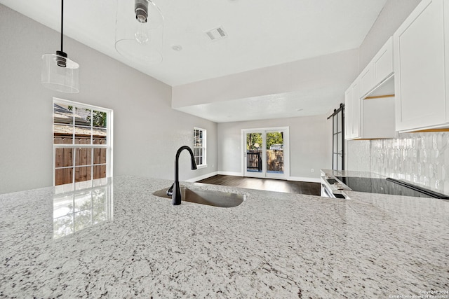 kitchen featuring light stone counters, dark hardwood / wood-style floors, white cabinets, sink, and hanging light fixtures