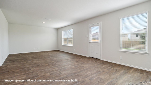 spare room with dark hardwood / wood-style floors and a healthy amount of sunlight