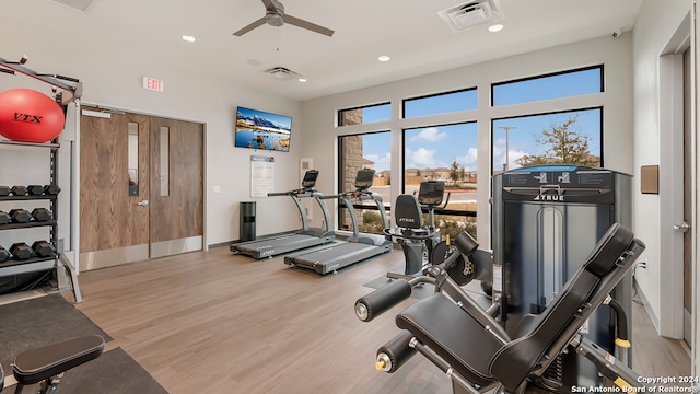 exercise room with ceiling fan and light hardwood / wood-style flooring