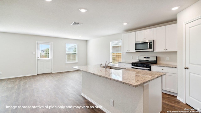 kitchen featuring gas stove, a center island with sink, hardwood / wood-style floors, and white cabinetry