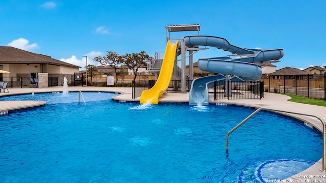 view of pool with a playground, a water slide, and pool water feature