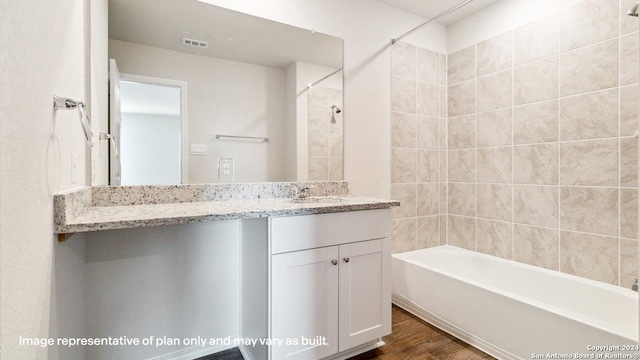 bathroom with wood-type flooring, tiled shower / bath, and vanity