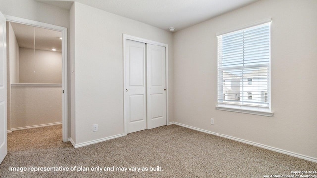 unfurnished bedroom featuring carpet floors, a closet, and multiple windows