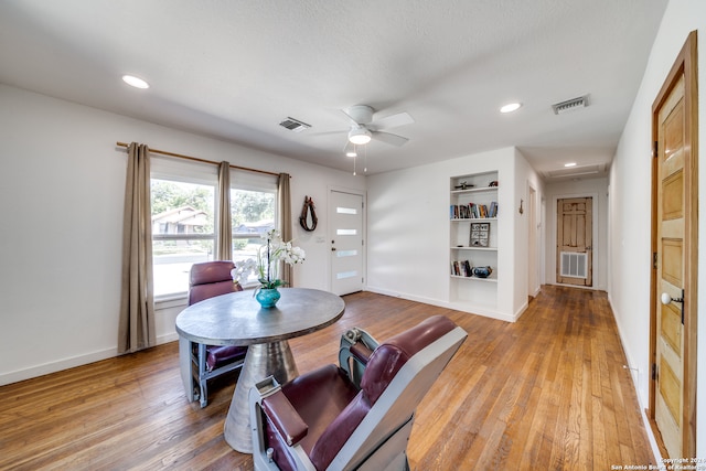 dining space with a textured ceiling, wood-type flooring, built in features, and ceiling fan