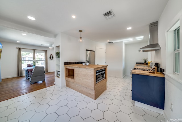 kitchen with butcher block countertops, appliances with stainless steel finishes, extractor fan, and light hardwood / wood-style flooring