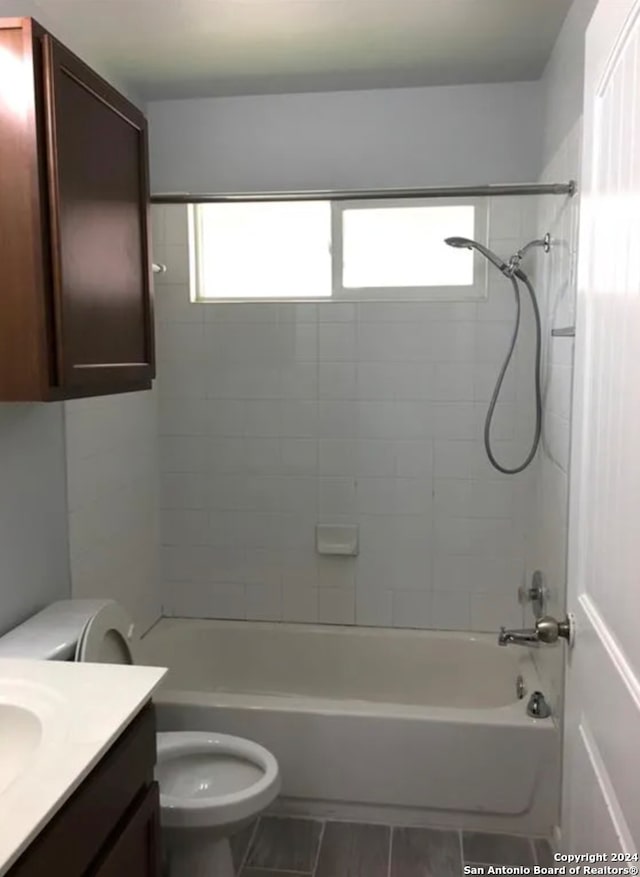 full bathroom featuring tiled shower / bath, vanity, and toilet