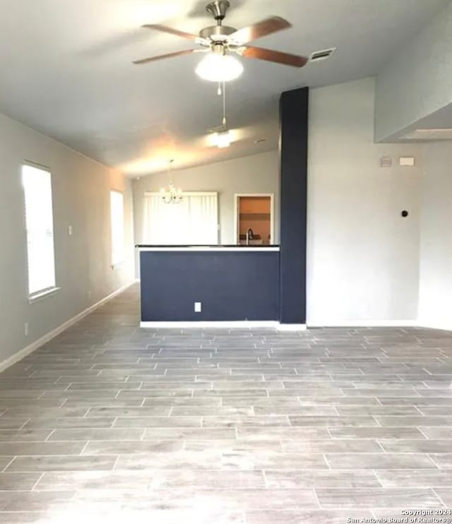 spare room featuring vaulted ceiling, ceiling fan with notable chandelier, and light hardwood / wood-style floors