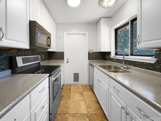 kitchen with white cabinets, sink, tasteful backsplash, a textured ceiling, and appliances with stainless steel finishes