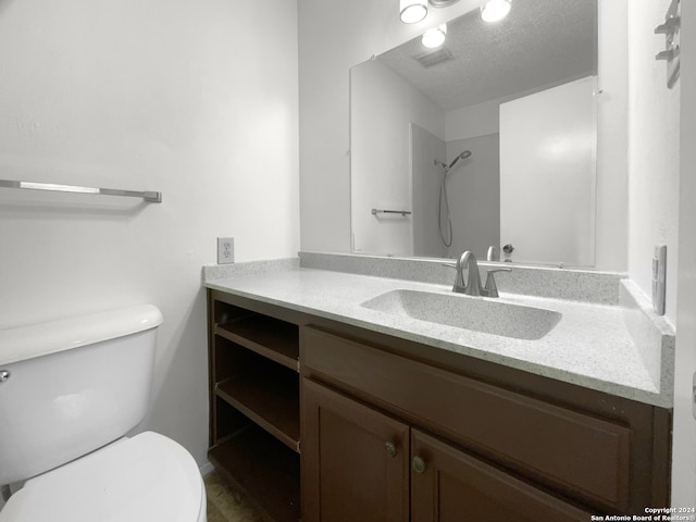 bathroom with a textured ceiling, a shower, vanity, and toilet