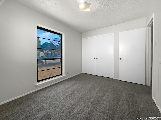 unfurnished bedroom with a closet, dark colored carpet, and a textured ceiling