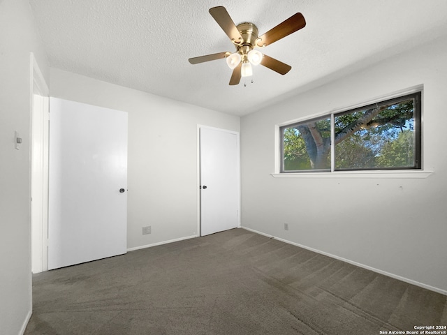 carpeted empty room with ceiling fan and a textured ceiling