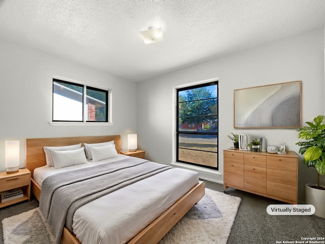 bedroom featuring multiple windows, carpet flooring, and a textured ceiling