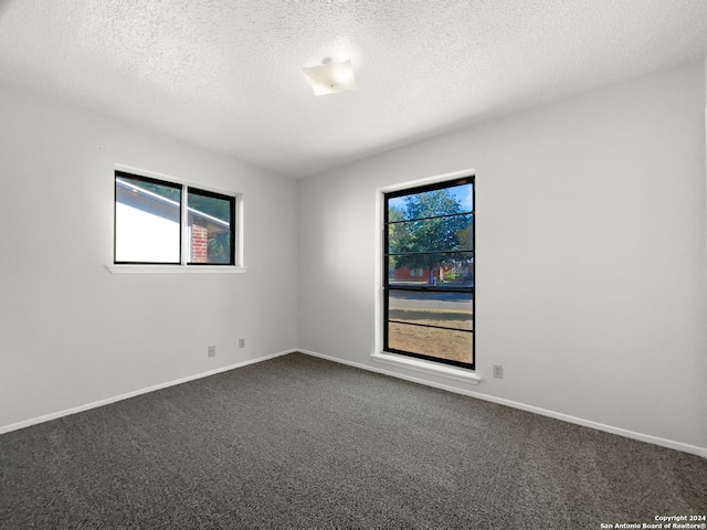 spare room featuring dark colored carpet and a textured ceiling