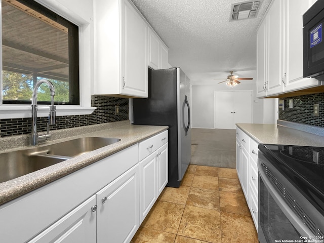 kitchen with decorative backsplash, sink, stainless steel appliances, light tile patterned floors, and white cabinetry