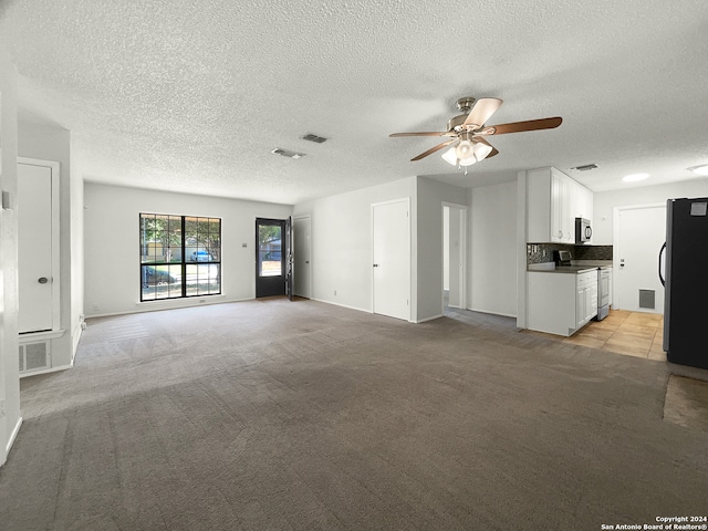 unfurnished living room featuring light carpet, ceiling fan, and a textured ceiling