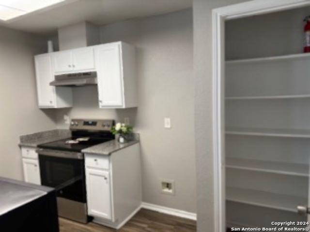 kitchen with white cabinetry, dark hardwood / wood-style floors, and stainless steel electric stove