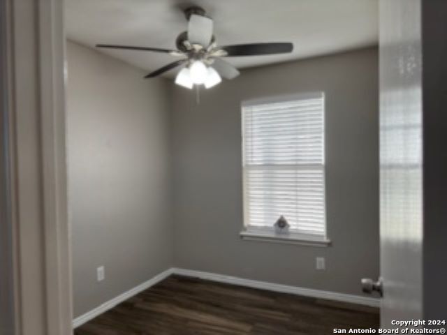 empty room with plenty of natural light, dark hardwood / wood-style flooring, and ceiling fan