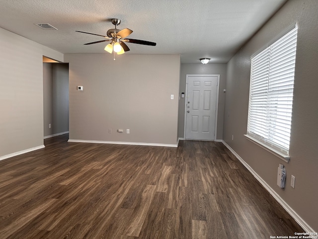 unfurnished living room featuring ceiling fan, a textured ceiling, and dark wood-type flooring