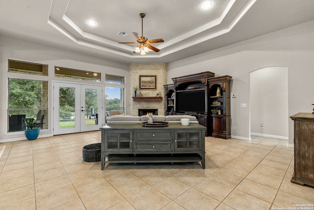 living room featuring light tile patterned flooring, french doors, a tray ceiling, and ceiling fan