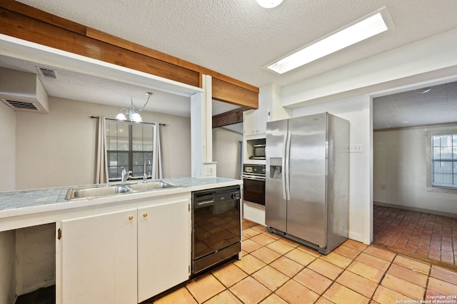 kitchen with stainless steel appliances, a sink, an inviting chandelier, white cabinetry, and tile counters