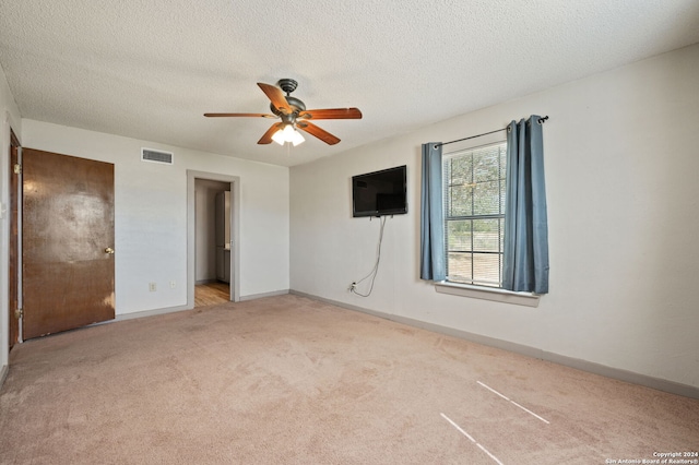 unfurnished bedroom featuring a textured ceiling, baseboards, visible vents, carpet, and ceiling fan