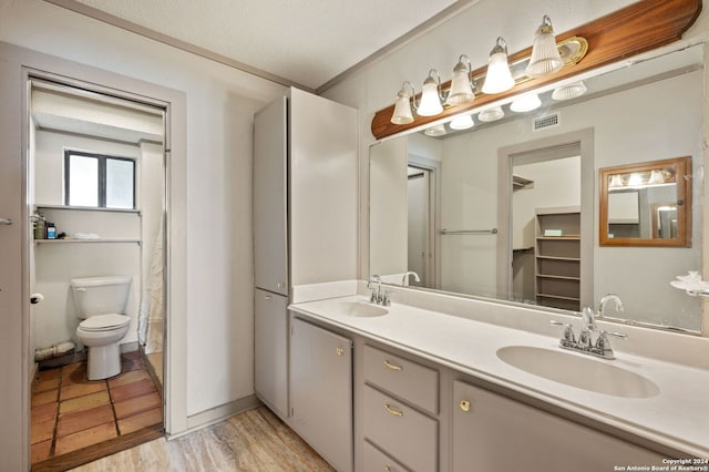 bathroom with a textured ceiling, ornamental molding, vanity, and toilet