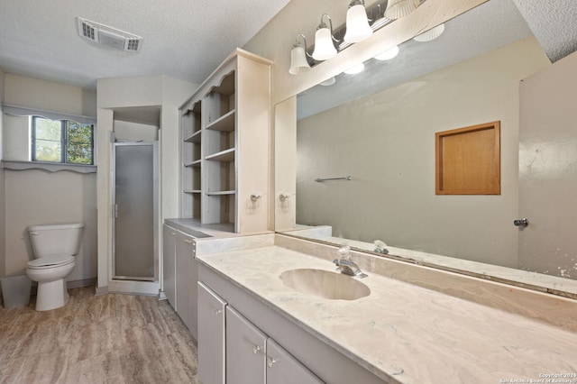 bathroom with vanity, walk in shower, wood-type flooring, toilet, and a textured ceiling