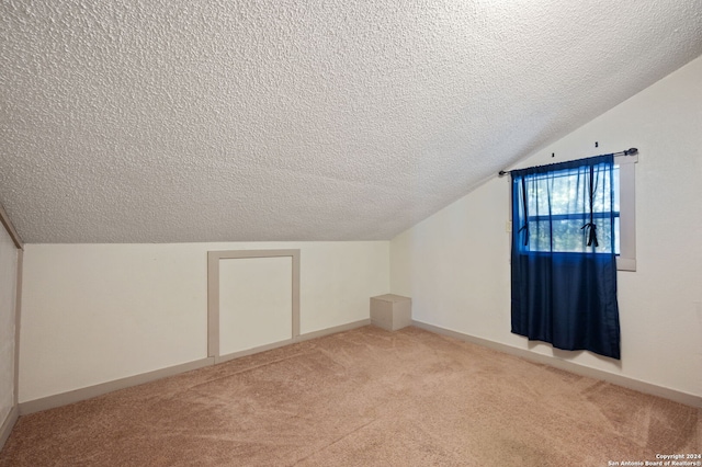 additional living space featuring lofted ceiling, a textured ceiling, baseboards, and light carpet