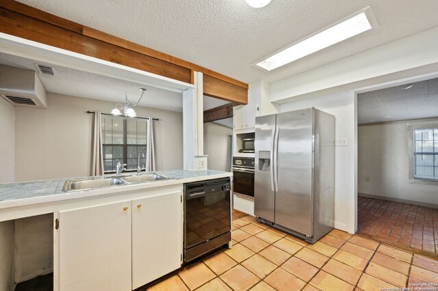 kitchen with stainless steel appliances, a sink, an inviting chandelier, white cabinetry, and tile counters