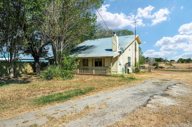 view of home's exterior with a porch, a chimney, and metal roof