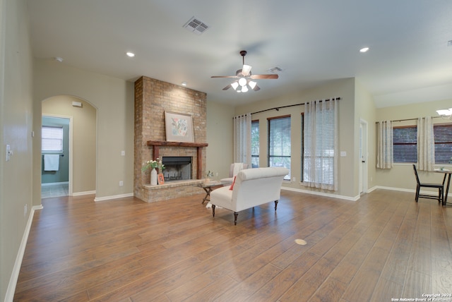 living room featuring hardwood / wood-style flooring, ceiling fan, and a fireplace