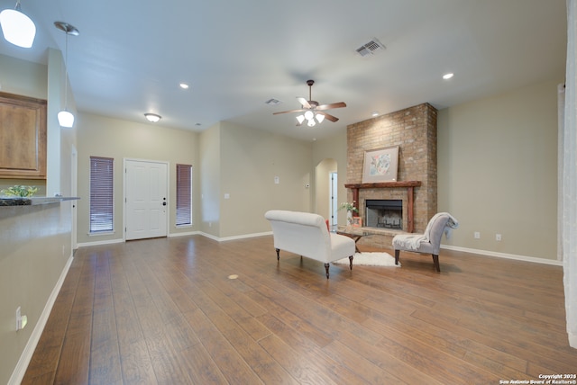 living room with dark hardwood / wood-style floors, a large fireplace, and ceiling fan