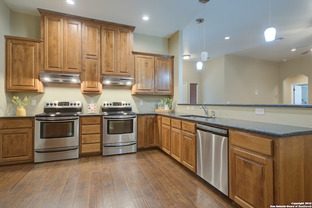 kitchen with kitchen peninsula, appliances with stainless steel finishes, sink, pendant lighting, and dark hardwood / wood-style floors