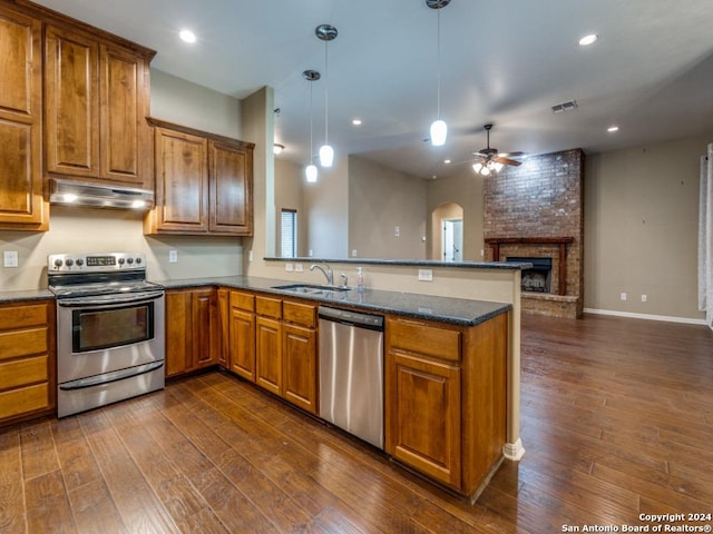 kitchen with under cabinet range hood, a sink, a peninsula, appliances with stainless steel finishes, and ceiling fan