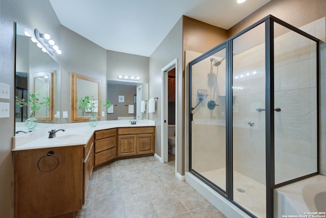 full bath with a sink, a shower stall, double vanity, and toilet