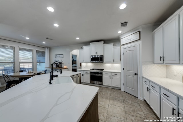 kitchen featuring white cabinetry, stainless steel appliances, decorative backsplash, and sink