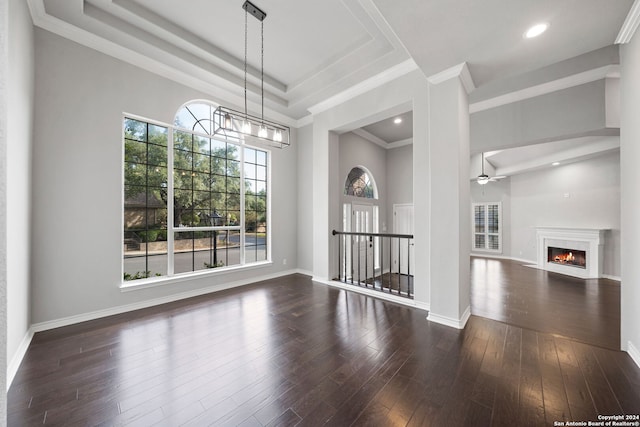 unfurnished dining area with ceiling fan with notable chandelier, crown molding, and dark wood-type flooring