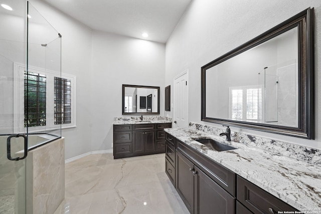 bathroom with a shower with door, a high ceiling, vanity, and a healthy amount of sunlight