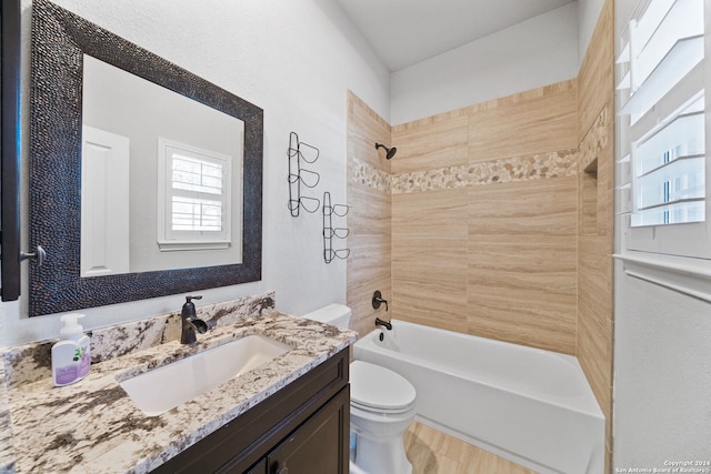 full bathroom featuring tiled shower / bath combo, vanity, and toilet