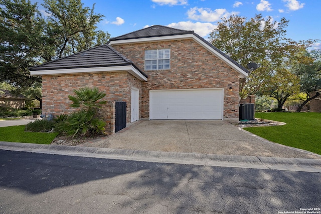 view of property featuring a front yard, central AC unit, and a garage