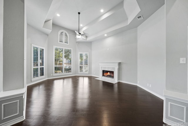 unfurnished living room featuring ceiling fan, a towering ceiling, and dark hardwood / wood-style flooring