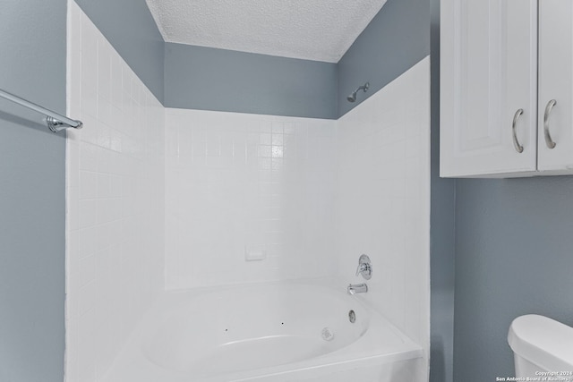 bathroom featuring washtub / shower combination, a textured ceiling, and toilet