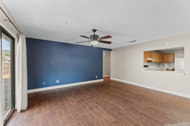 unfurnished living room with ceiling fan, a textured ceiling, sink, and dark wood-type flooring