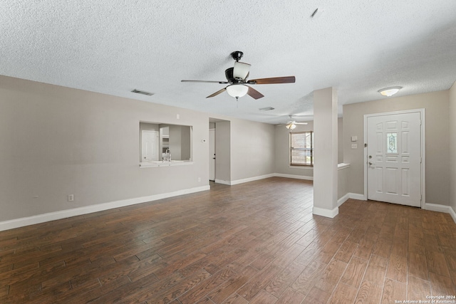 unfurnished living room featuring ceiling fan, dark hardwood / wood-style flooring, and a textured ceiling