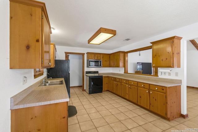 kitchen with refrigerator, white range with electric stovetop, sink, light tile patterned floors, and a textured ceiling