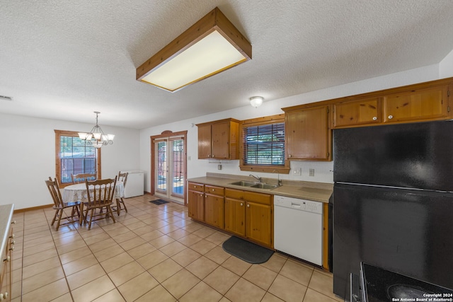 kitchen with black fridge, white dishwasher, sink, decorative light fixtures, and an inviting chandelier