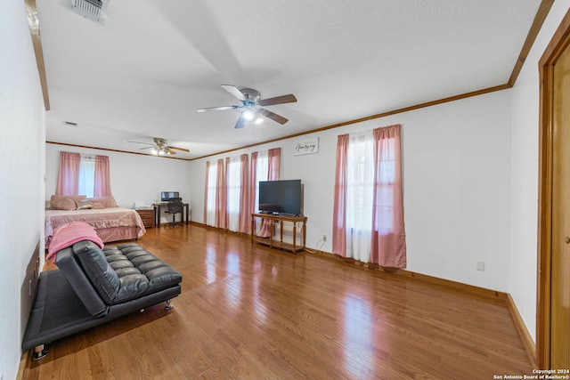 bedroom with ceiling fan, a textured ceiling, crown molding, and hardwood / wood-style floors