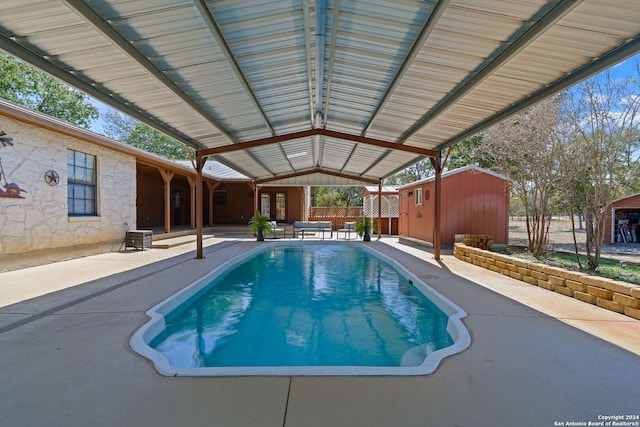 view of swimming pool featuring central AC unit, a storage unit, and a patio area