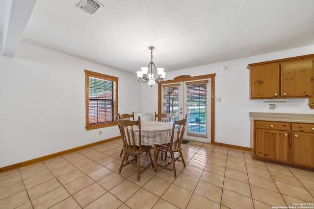 dining area with a notable chandelier, light tile patterned floors, a textured ceiling, and a healthy amount of sunlight