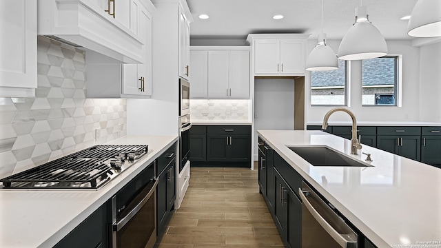 kitchen with sink, white cabinetry, stainless steel appliances, pendant lighting, and custom exhaust hood